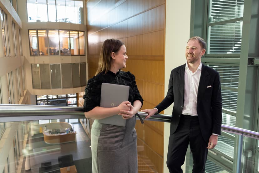 Two professionals engaged in a conversation within an office environment. 