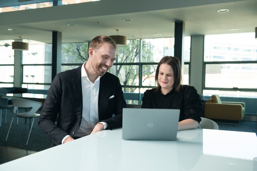 Two people discussing in front of a laptop in a corporate office