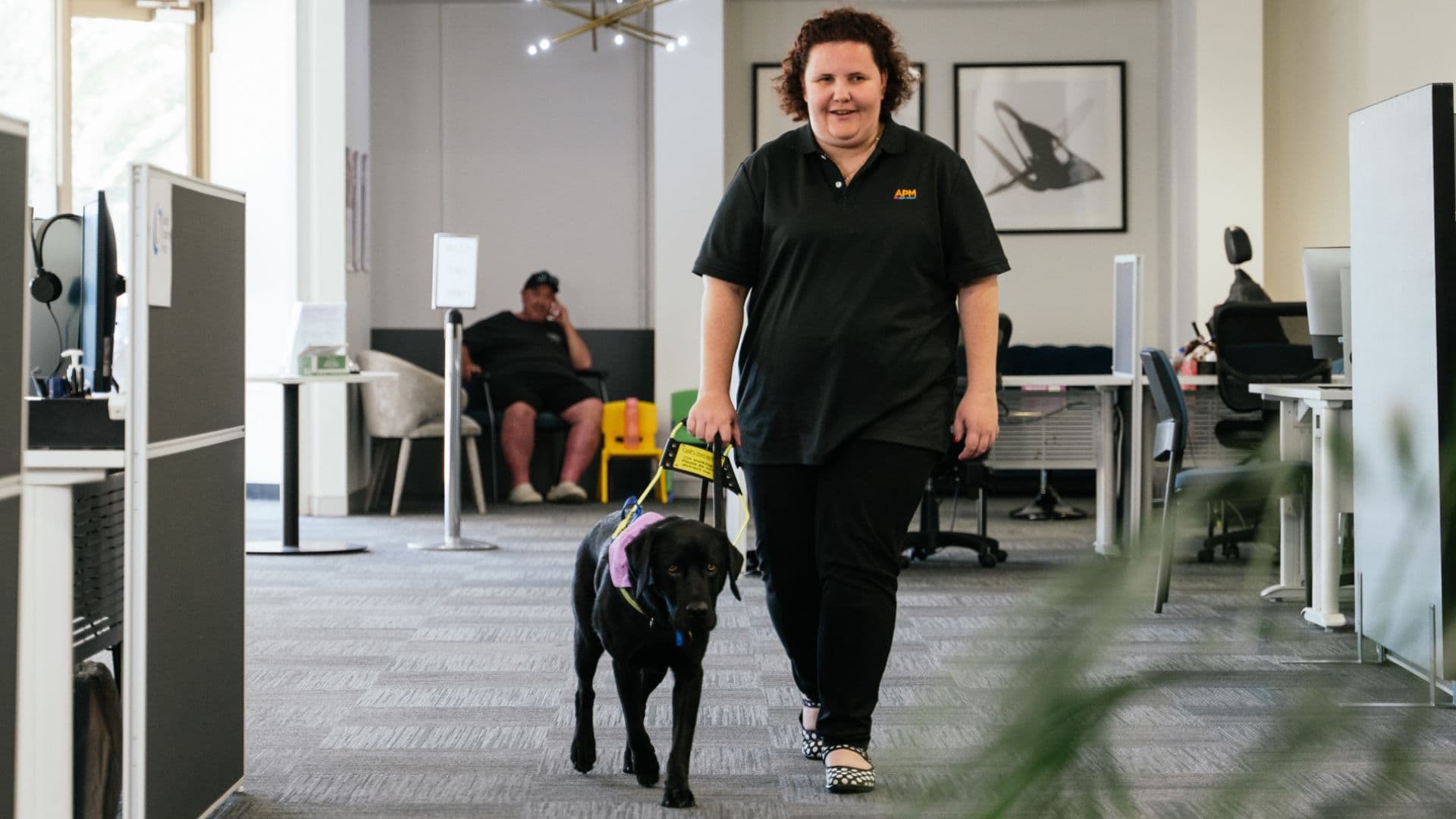 Aleysha from APM Communities walks through an office with her assistance dog.