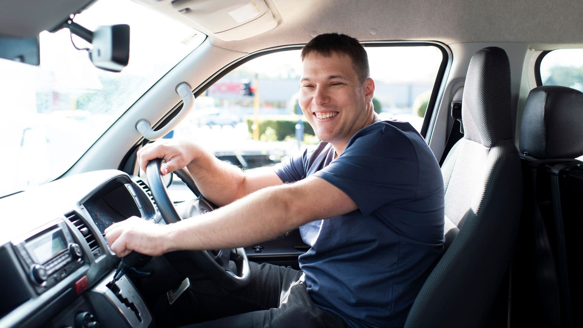Man smiles behind the wheel of work car