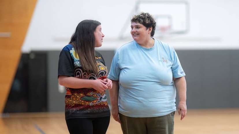 Kim and Natalie walk together in a sports hall.