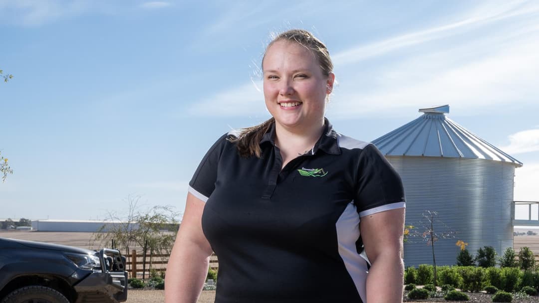 A woman smiles outside an agricultural building