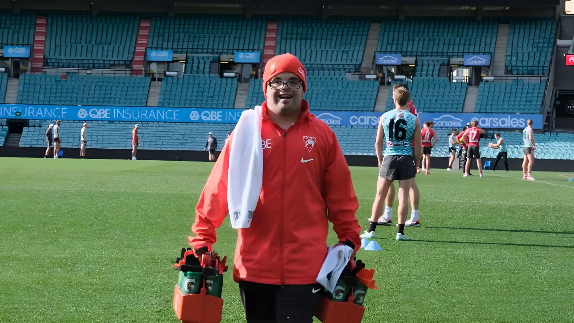 Adam wears his Sydney Swans employee kit as he delivers  water bottles during traiining