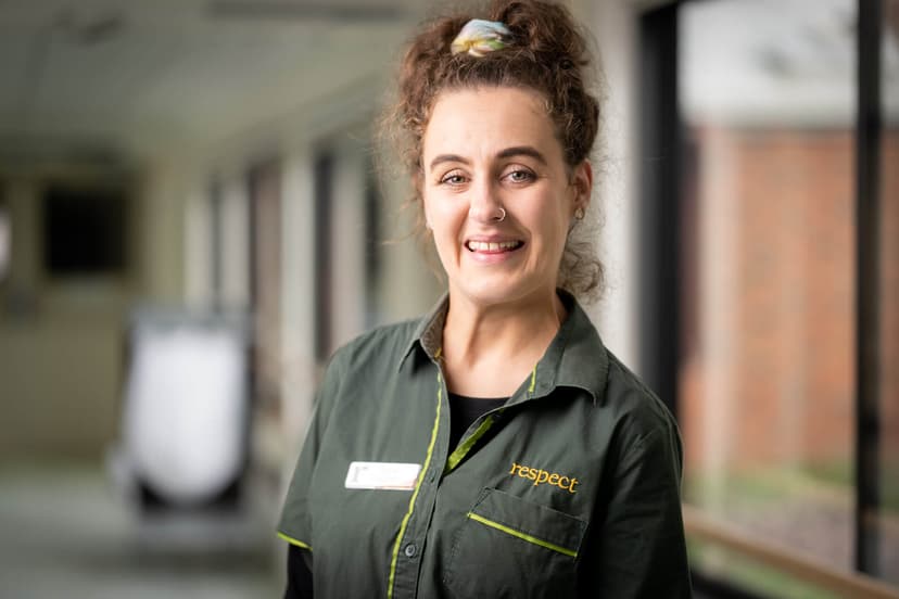 DES participant Tayla in dark green uniform smiles in a hallway