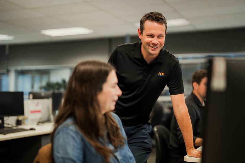 Male APM WorkCare Consultant engaging with a female office worker at a computer work station