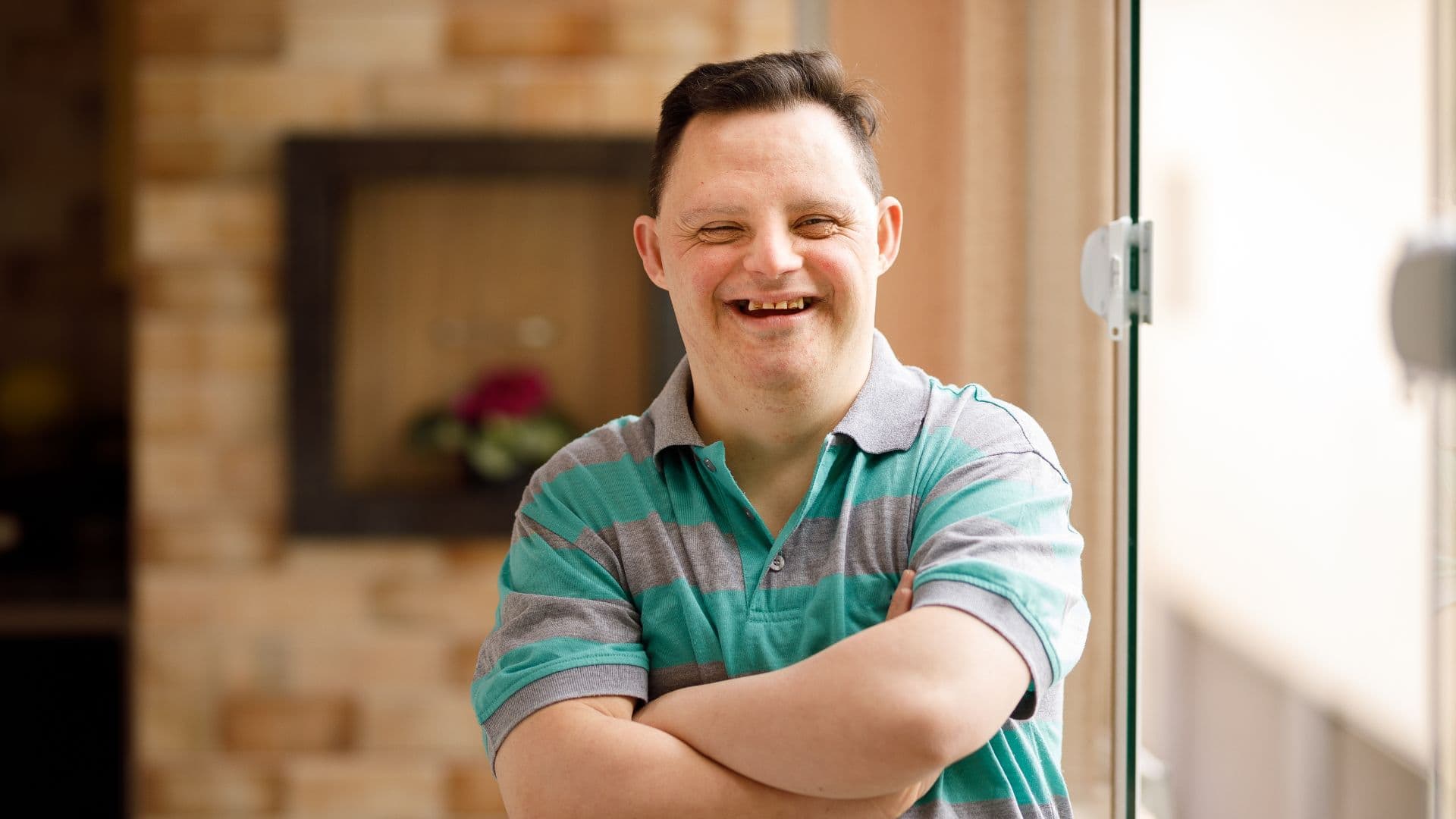 erson smiling with arms crossed while standing indoors