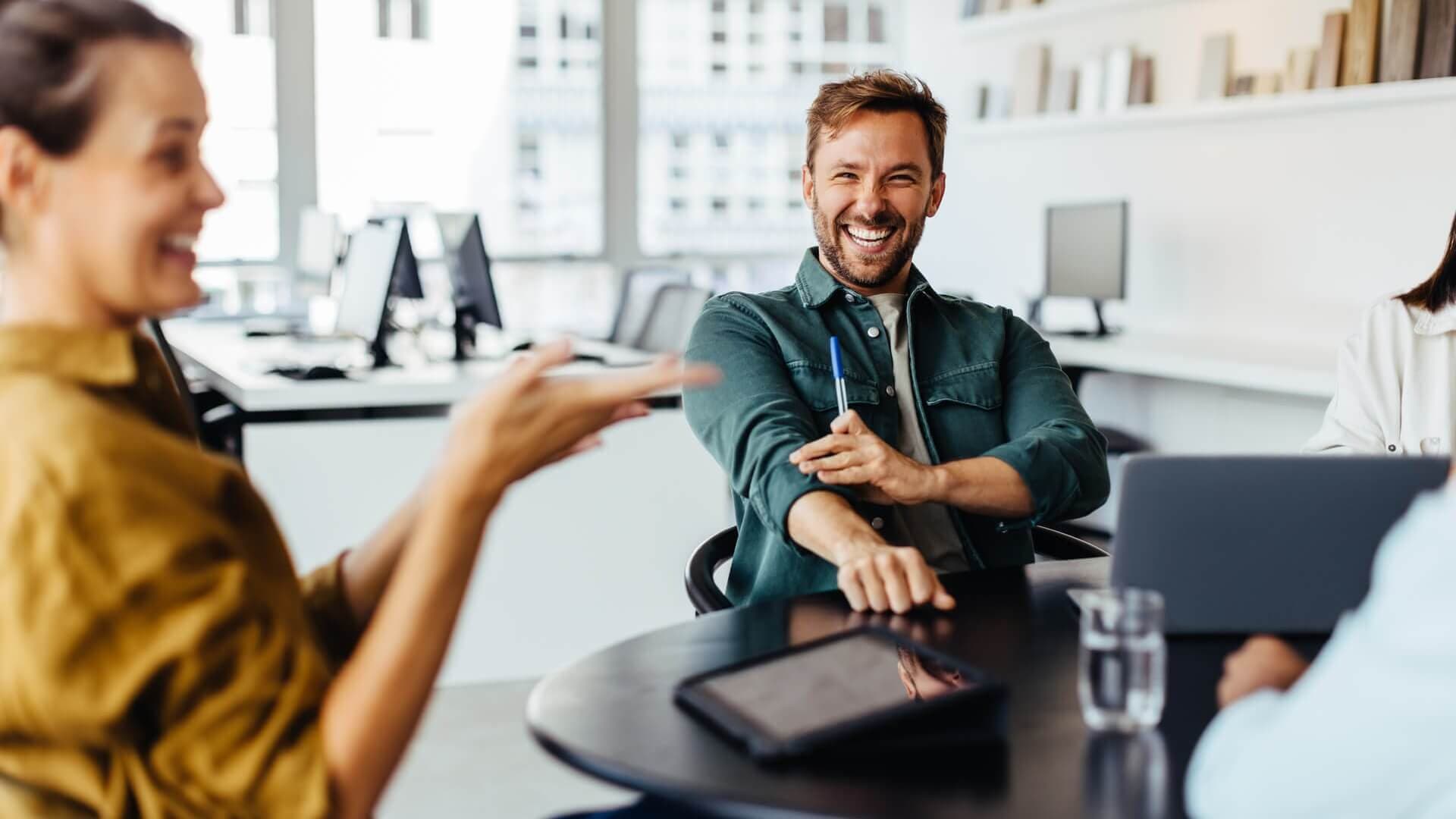 Office workers laugh together during meeting