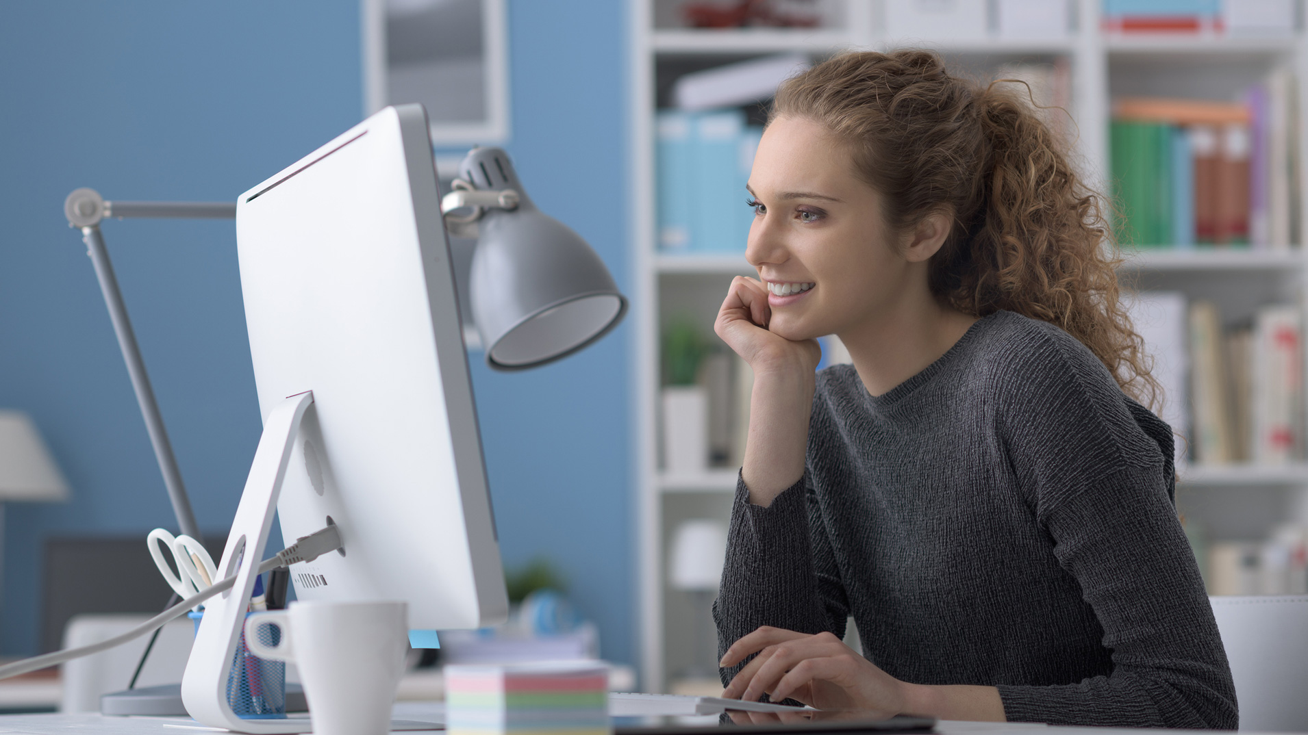 Woman smiling at desktop tackling work to do list