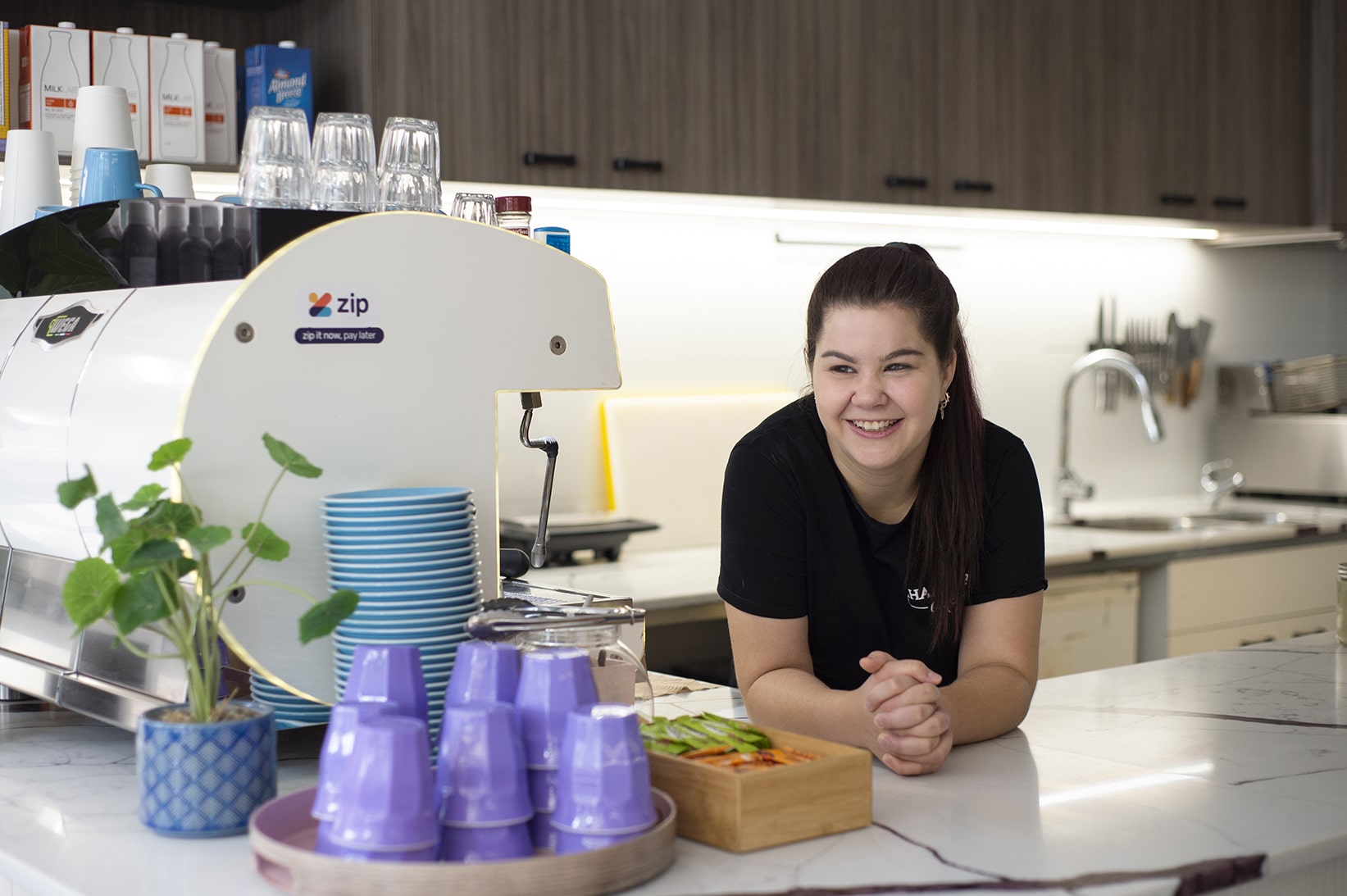 A young woman leans on the counter of a cafe