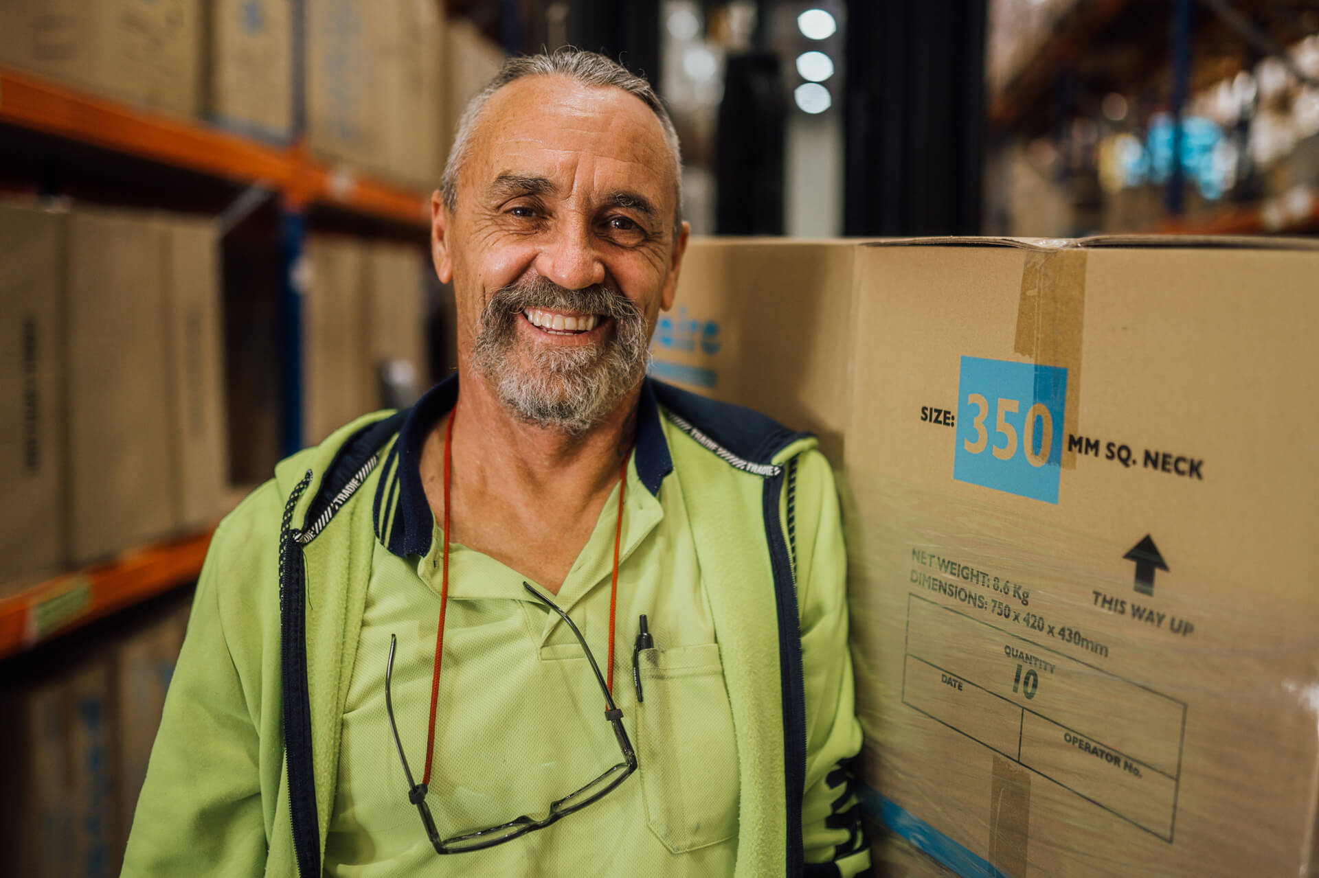 DES participant Mark smiles in a warehouse next to boxes