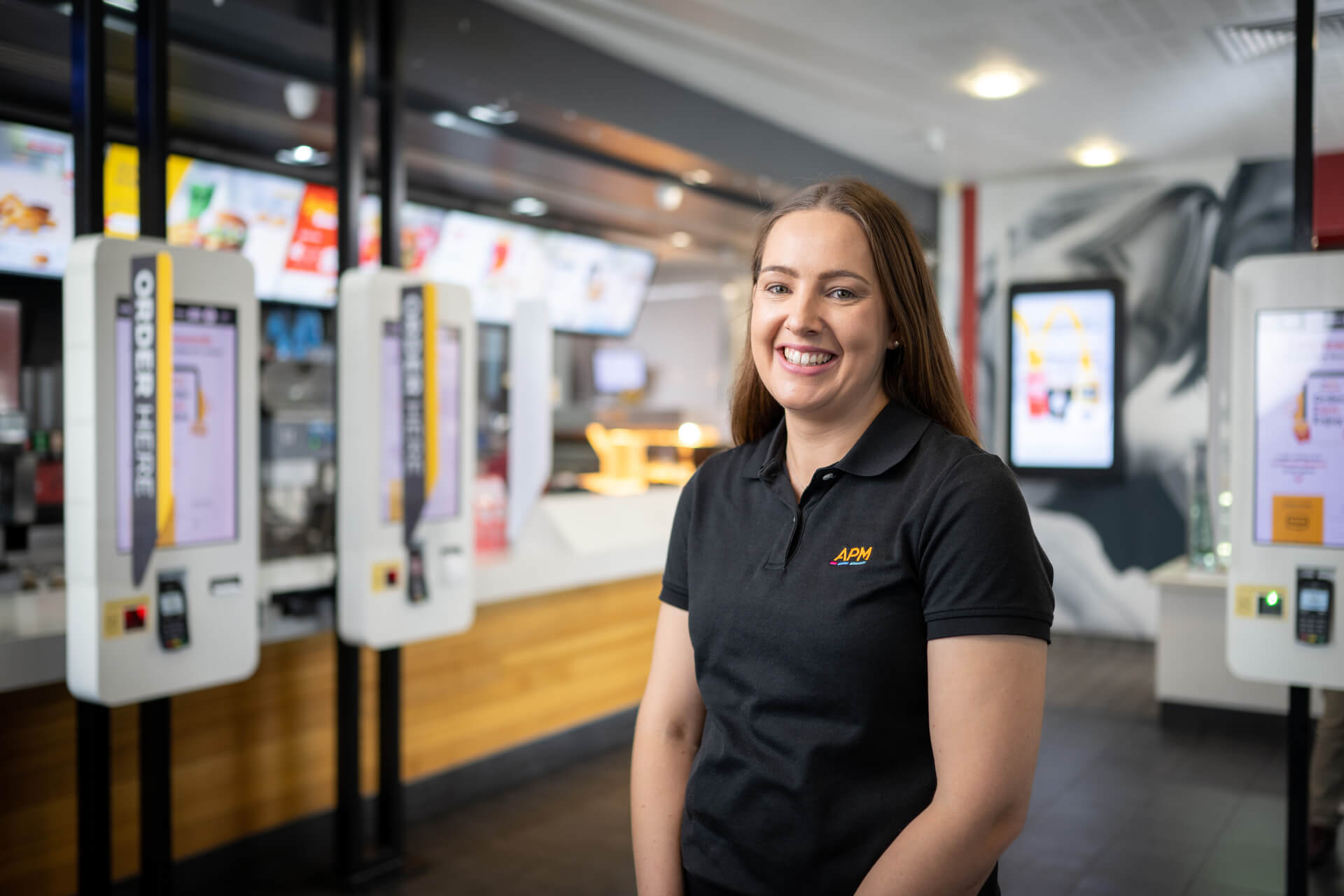 APM EC Samantha in a black polo smiles in a restaurant