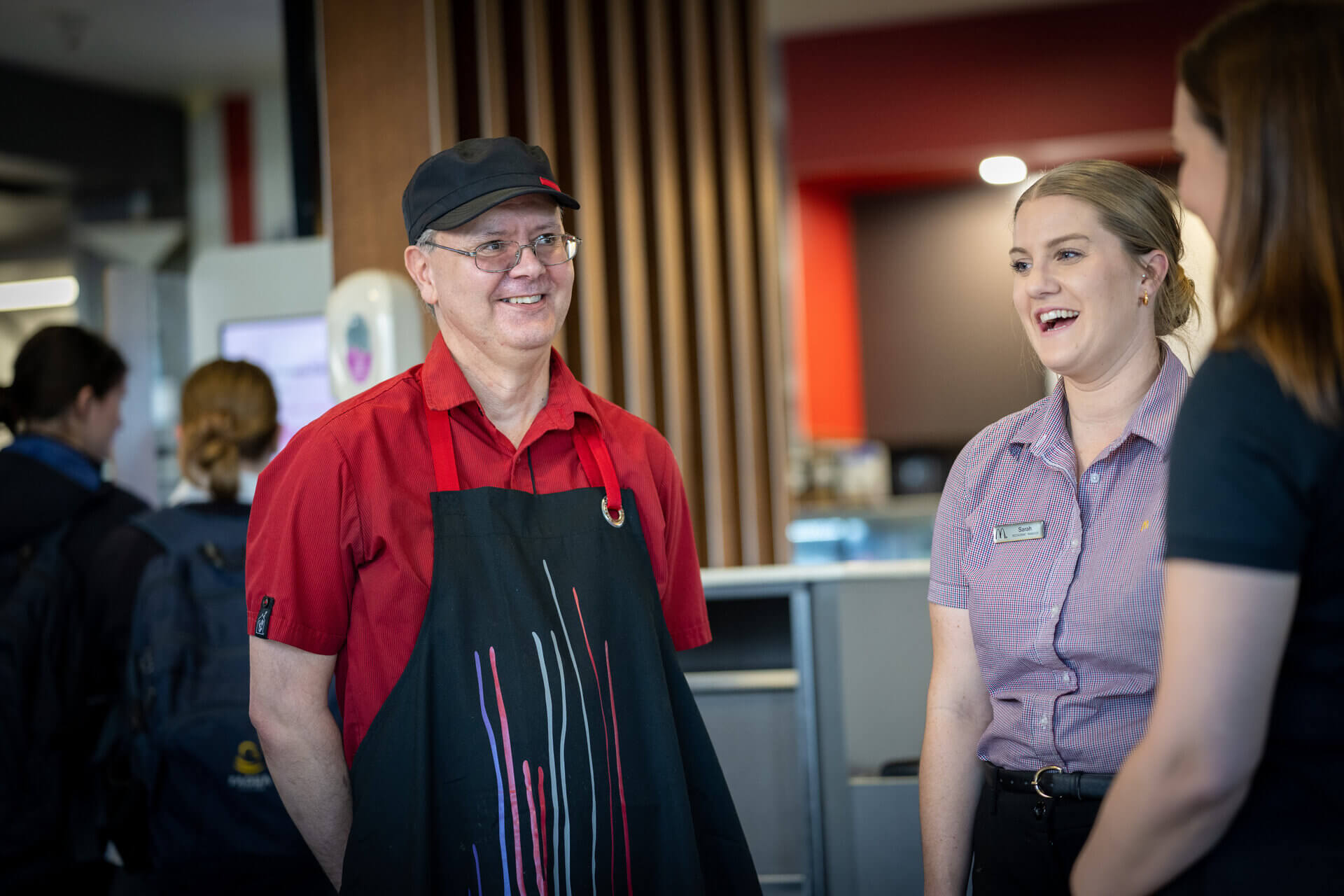 A man in an apron smiles with his employer in a purple shirt