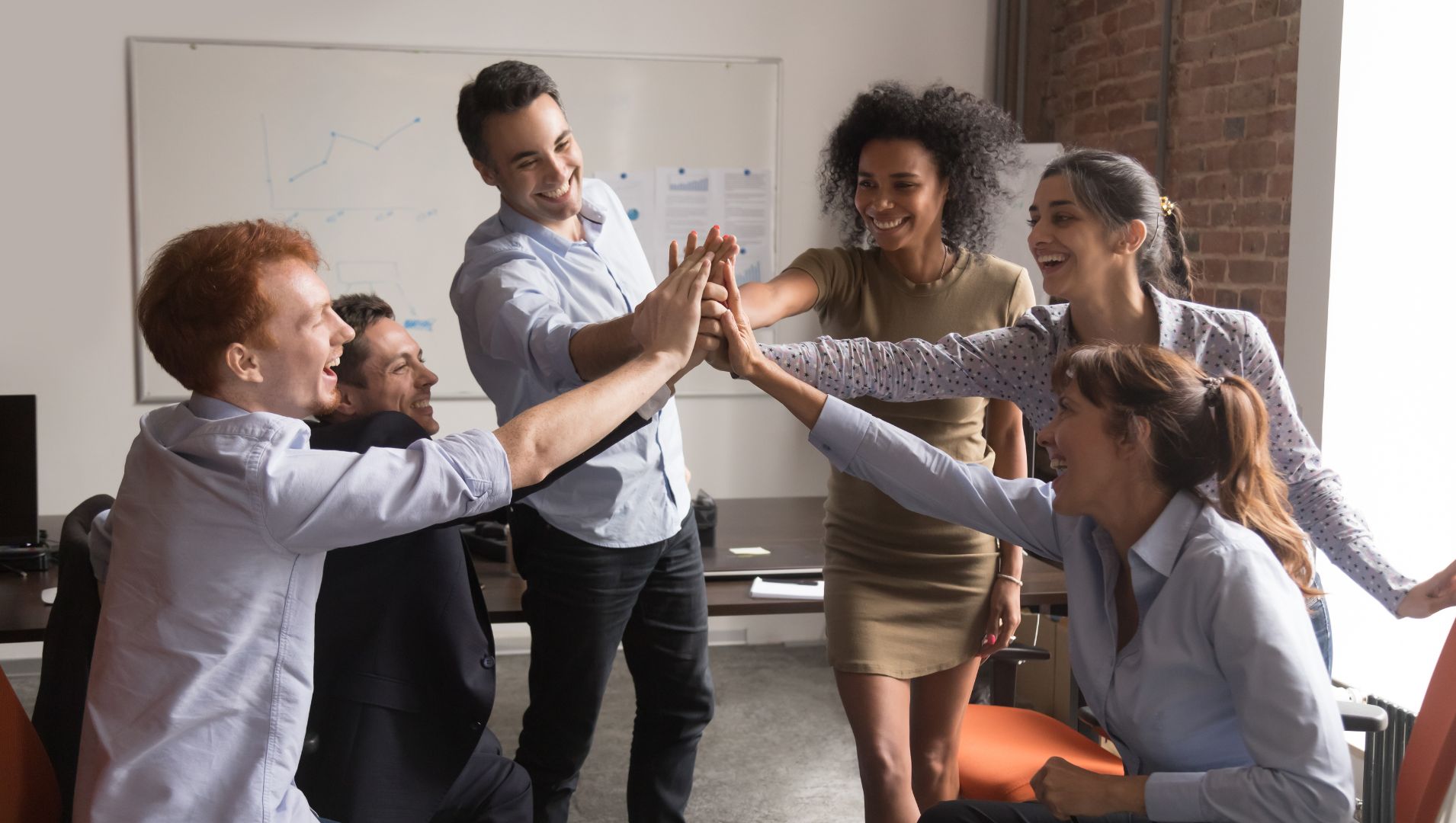 Team celebrates in an office with hands in a circle