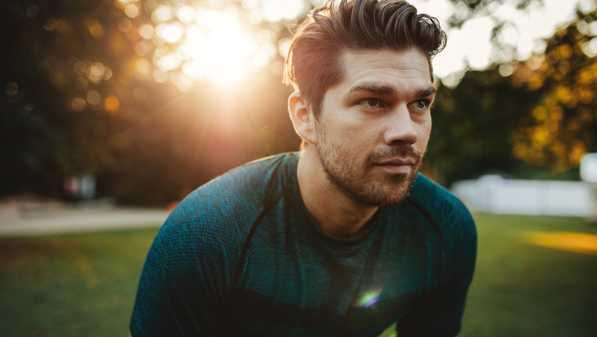 Man looks into the distance in fitness gear during workout as sun rises in a park