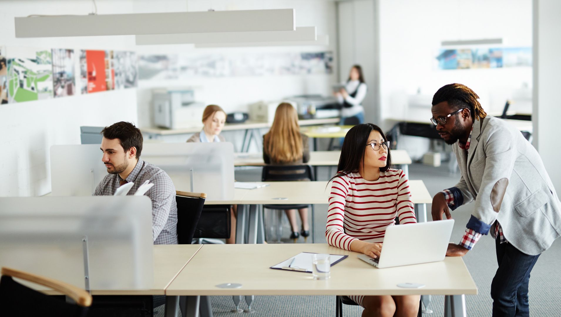 Colleagues talk in open communication in  a large open-plan office