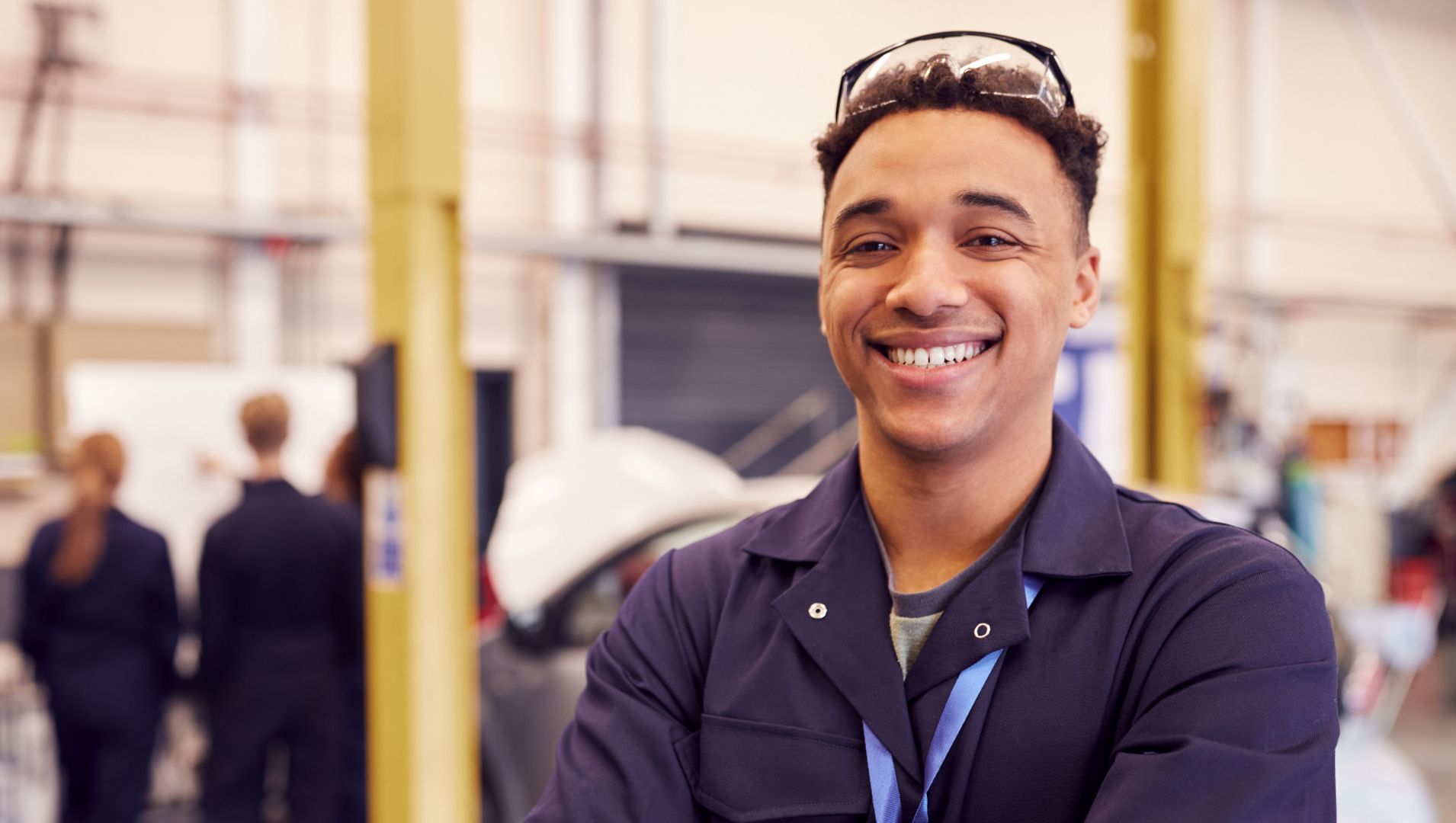 Young male apprentice smiles at camera in warehouse