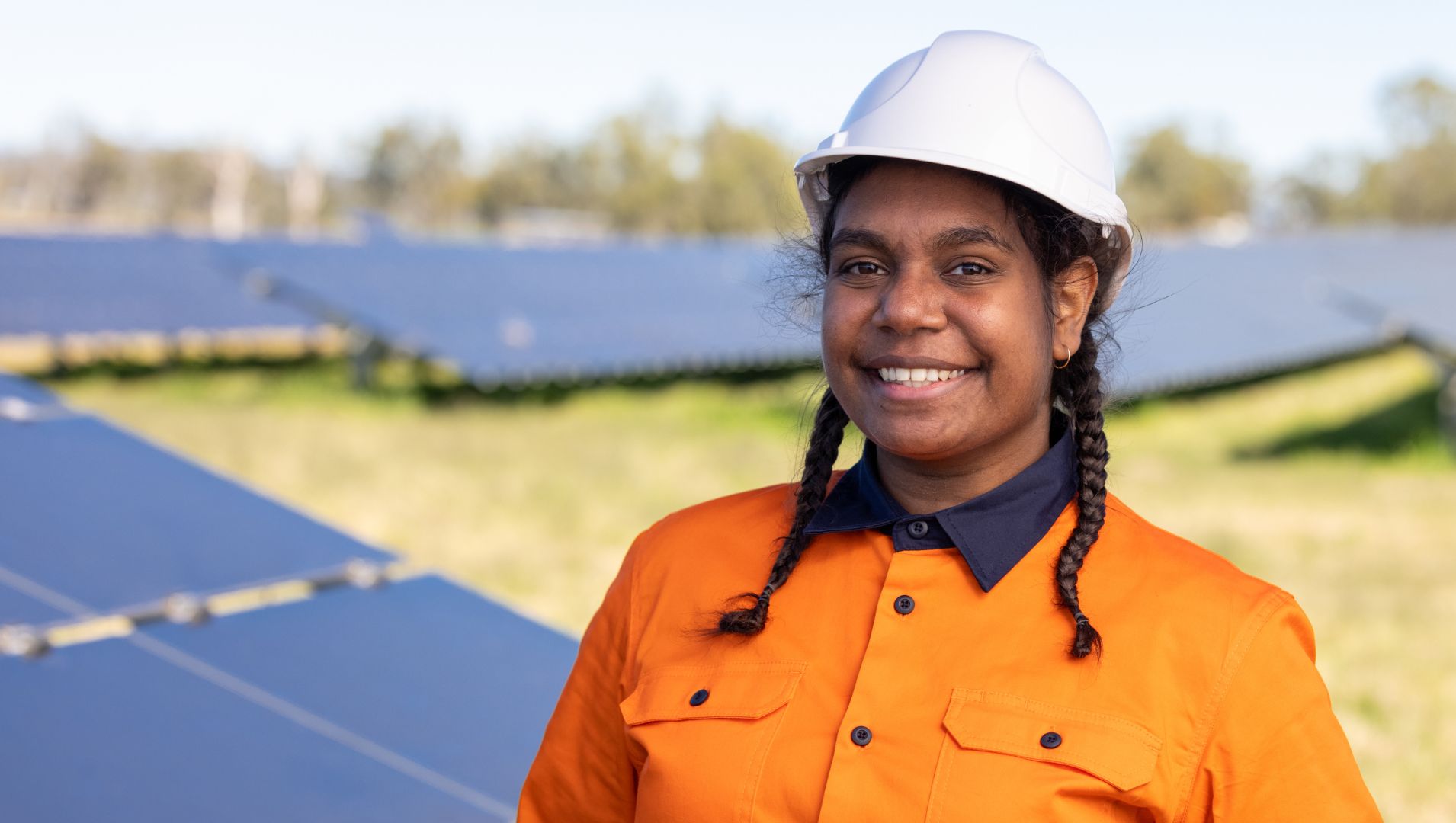 Female First Nations apprentice in hard hat and in solar farm