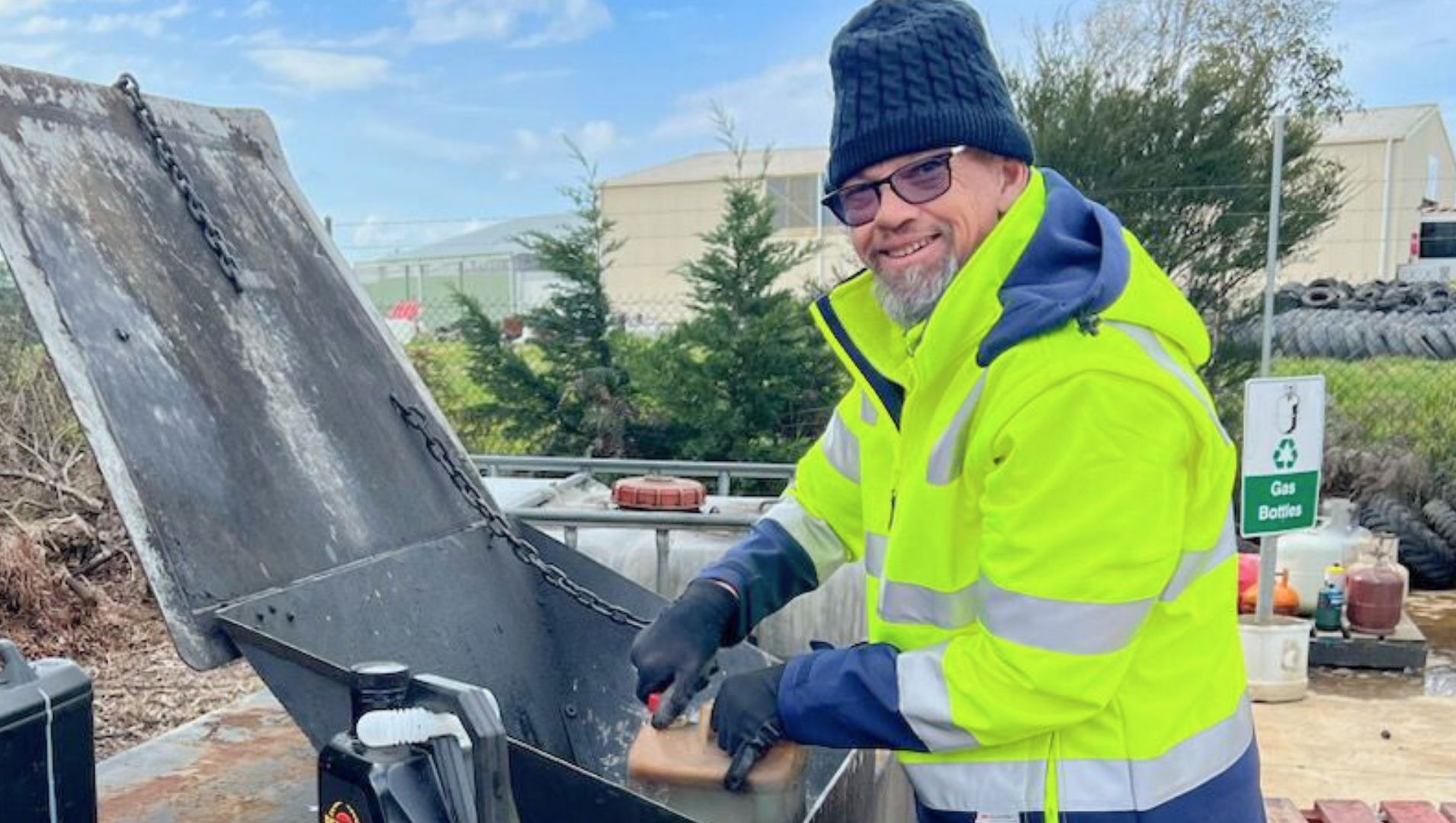 DES participant smiles through a large tyre at his job he found with support from APM Employment Services