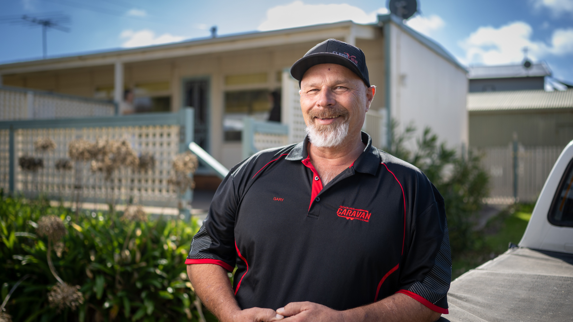 DES participant Gary smiles and leans on a ute outside his house