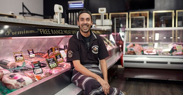 A male butcher with a disability smiling at store counter
