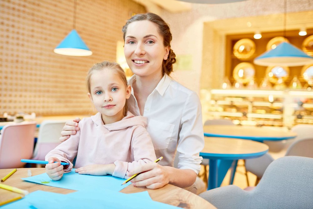 Parent with child at a cafe colouring paper