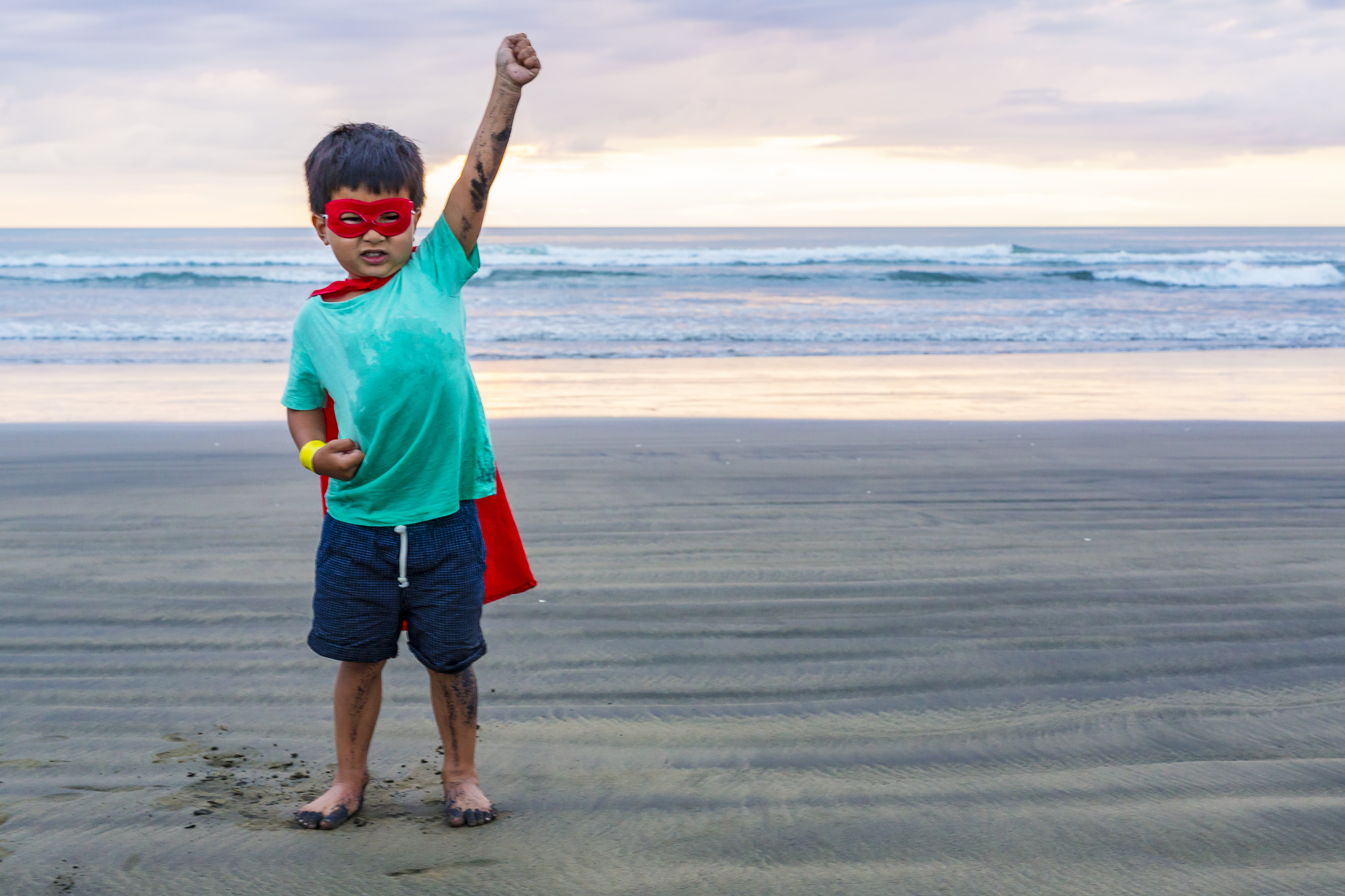 Child in super hero attire on the beach