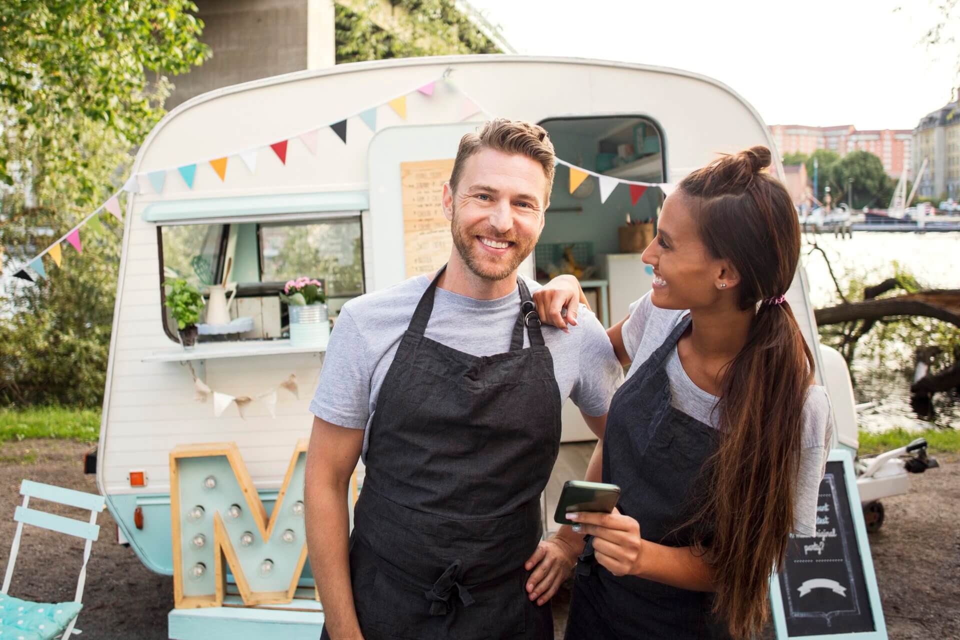 two people wearing aprons in front of a coffee van