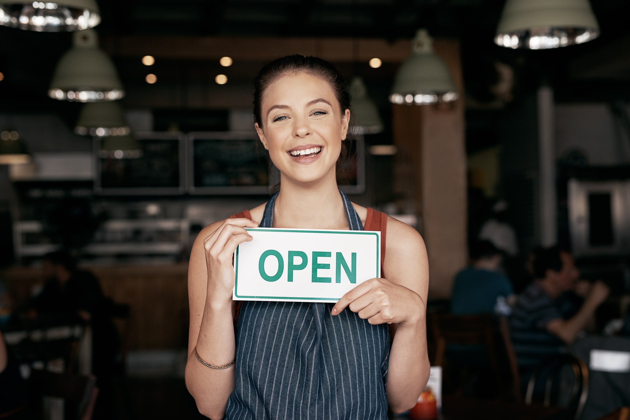 Woman holding open sign at cafe door