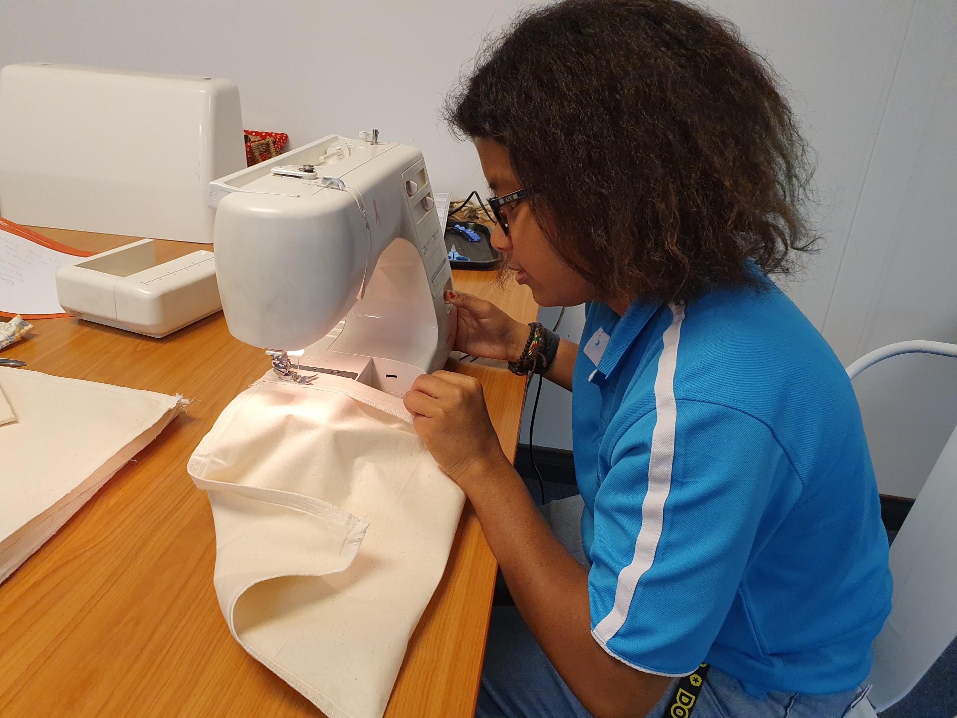 Faradiba at work, sitting with a sewing machine