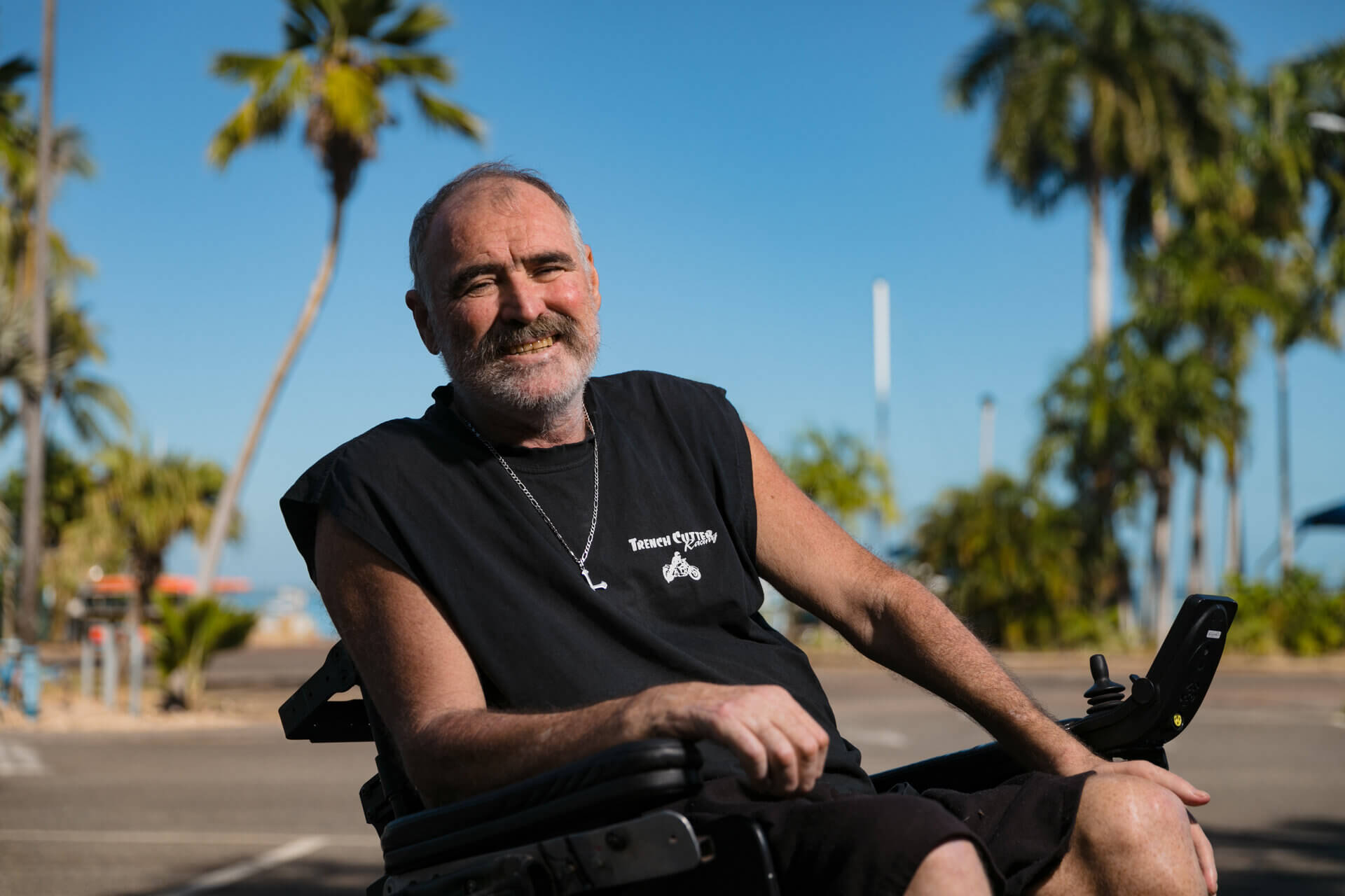 A smiling Paul McKenzie sits in a wheelchair