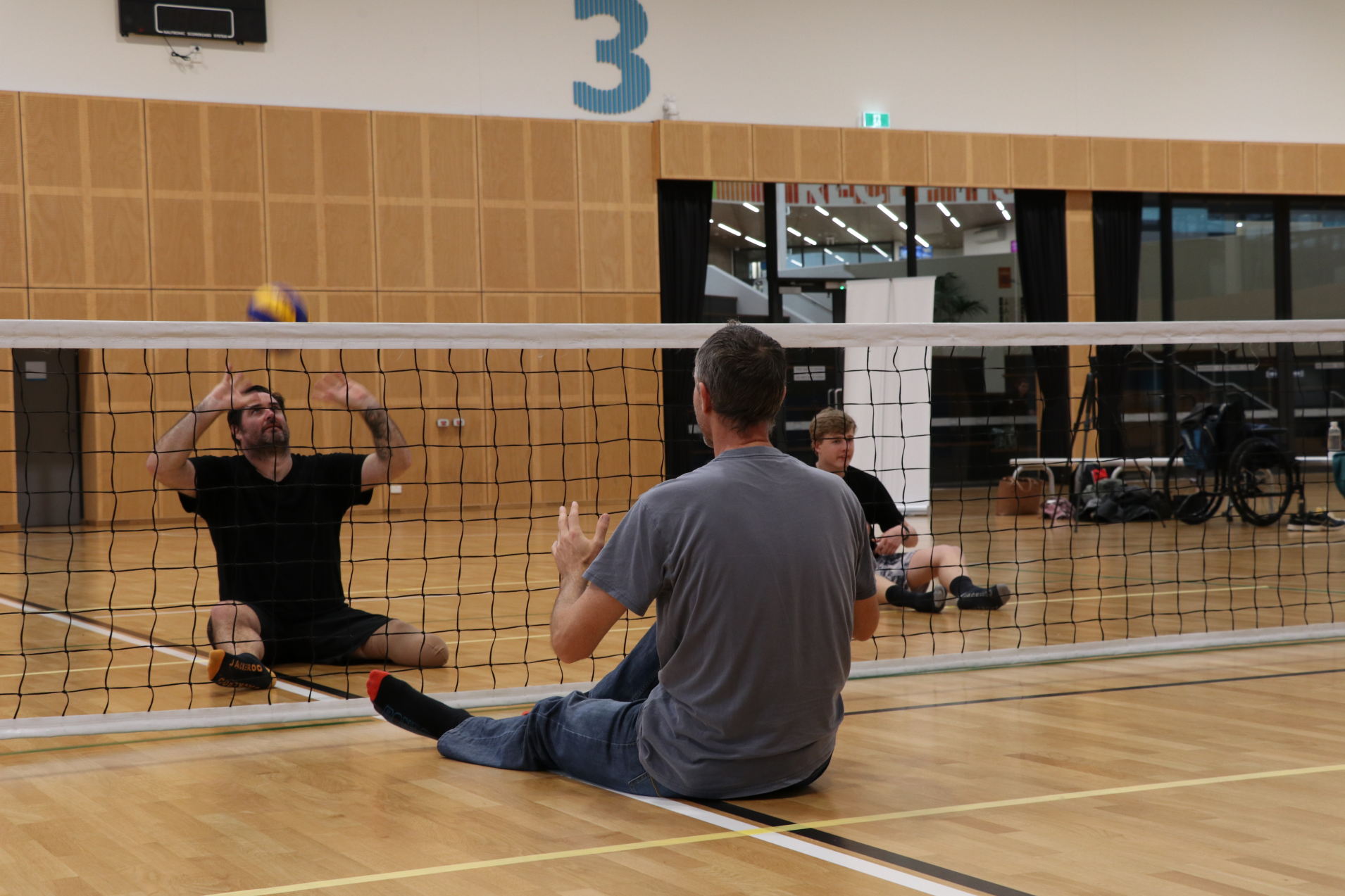 two seated volleyball players hit the ball to each other over a net
