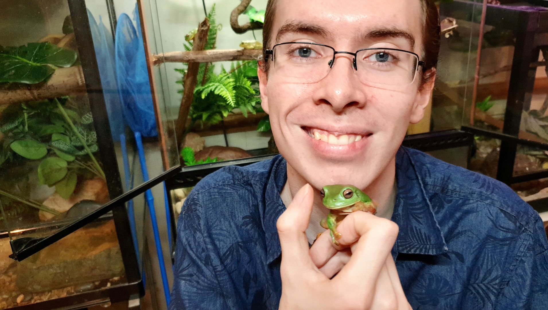 Aiden is pictured in the centre of the photo smiling with a green tree frog in his hand