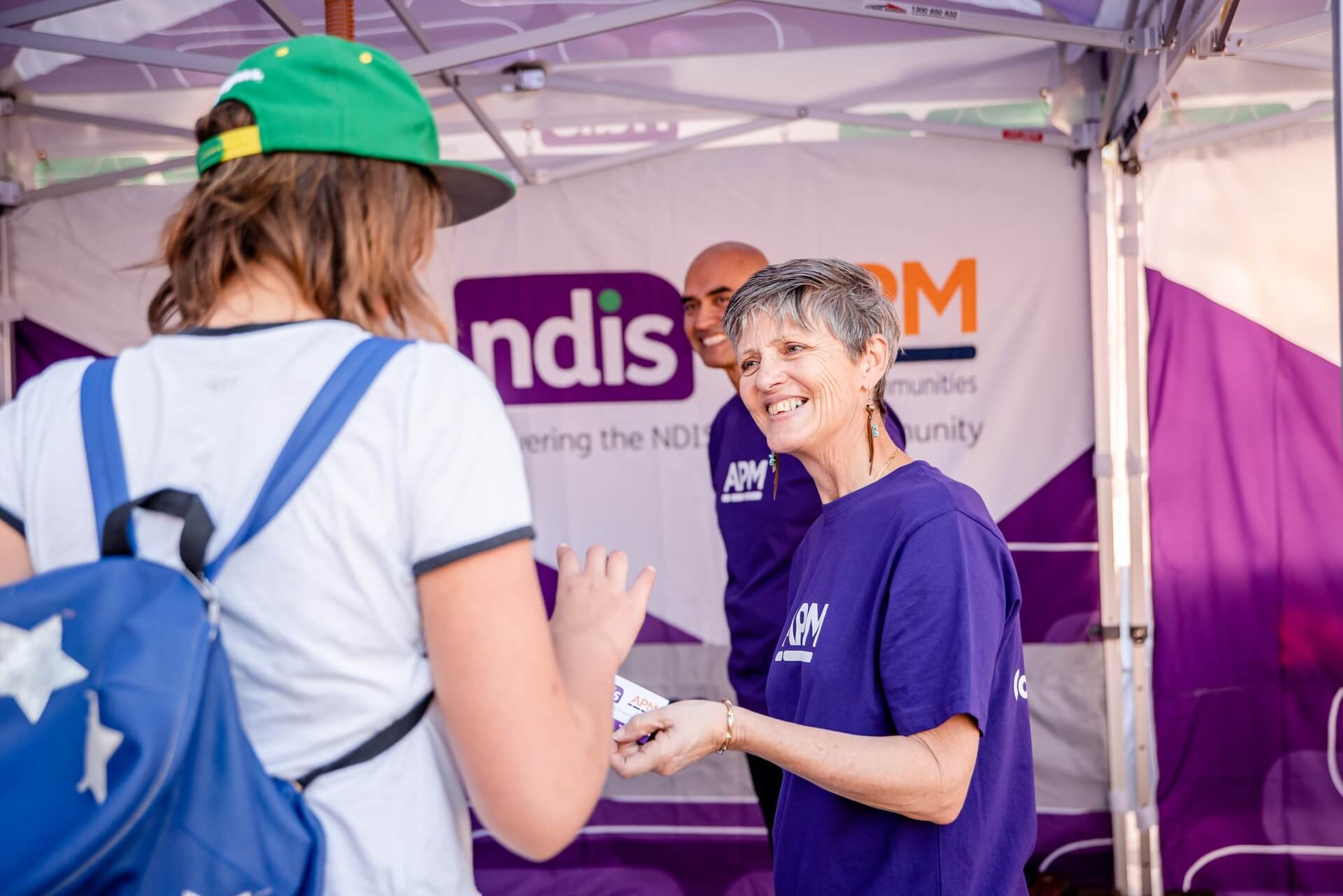 NDIS APM employee handing out cards smiling