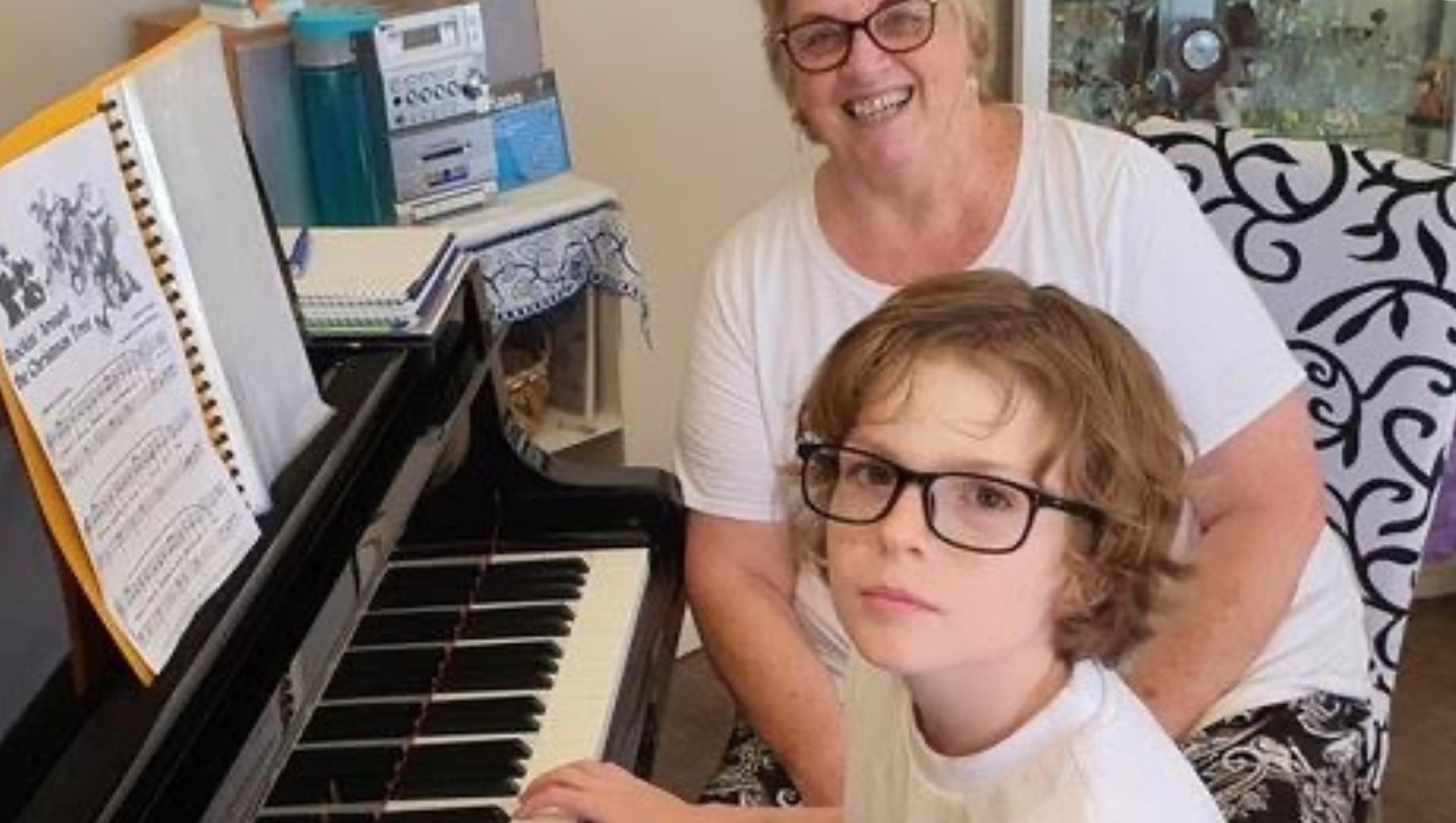 charlie and his music teacher sitting at the electric piano during a lesson in their home