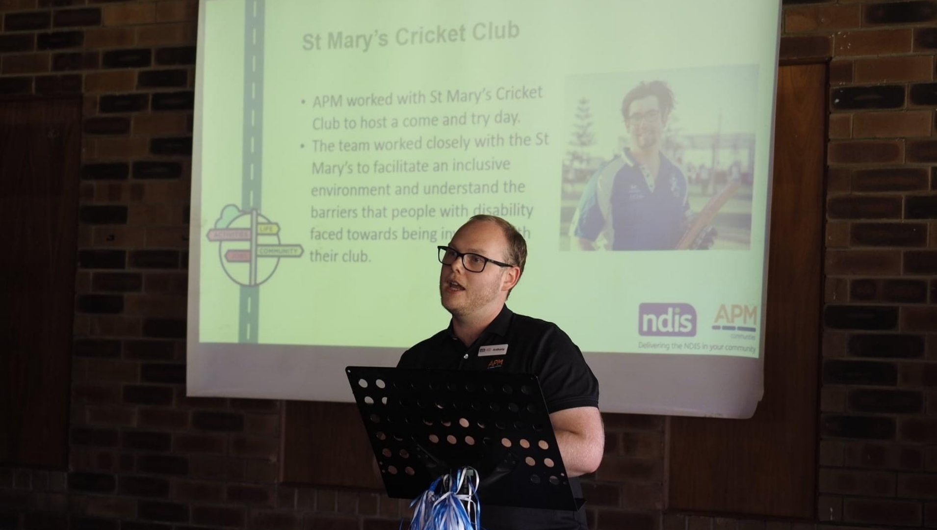 APM Communities staff member Anthony Pyle is pictured speaking at an event with a powerpoint slide in the background