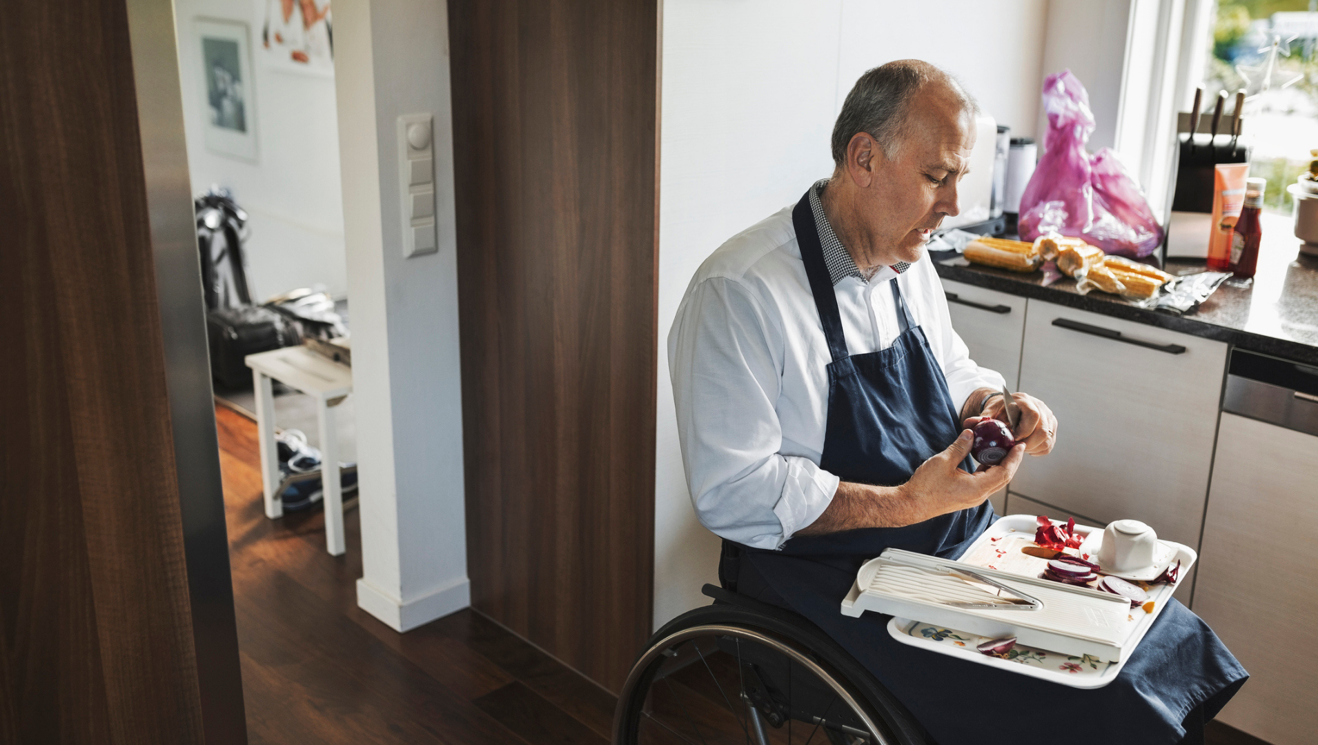 A man in a wheelchair in the kitchen chopping vegetables