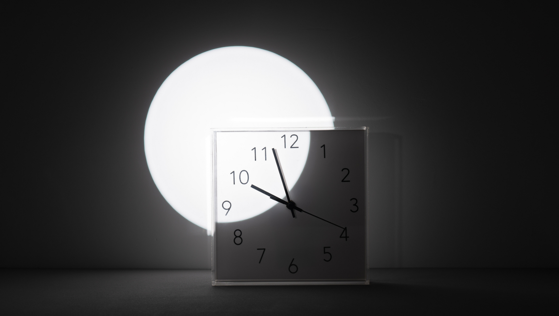 A clock, whose face is partially lit by a circle of light