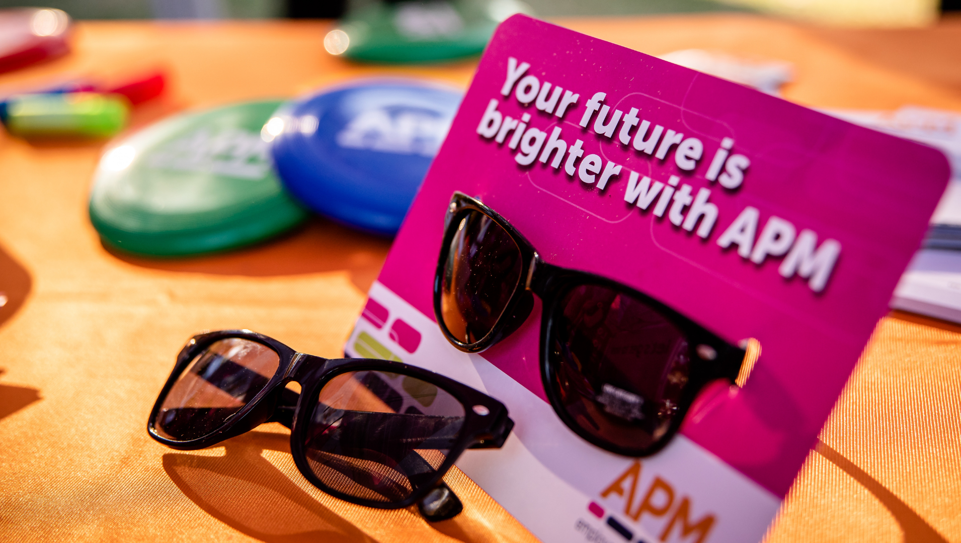 Table covered with APM branded paraphernalia, with the wording "Your future is brighter with APM" in the foreground