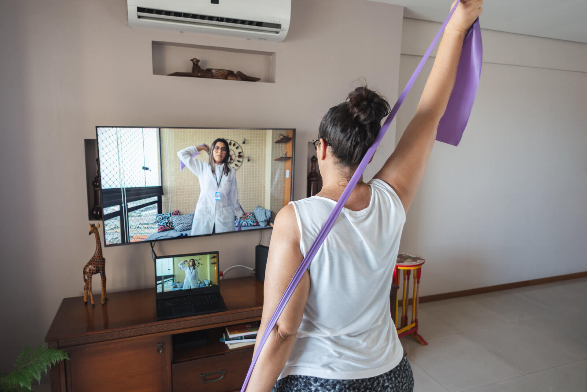 woman doing exercises in front of telehealth