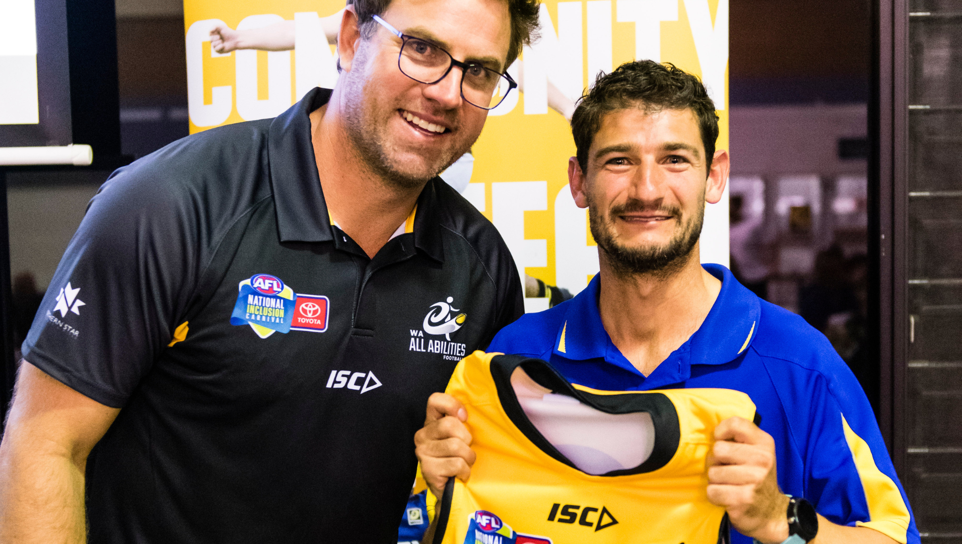 Two men smiling, holding a football jumper