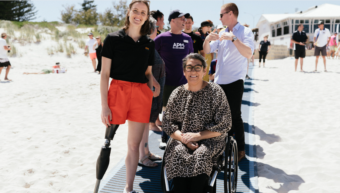 Ellie Cole standing next to a woman in a wheelchair on the mobi mat at Mullaloo Beach