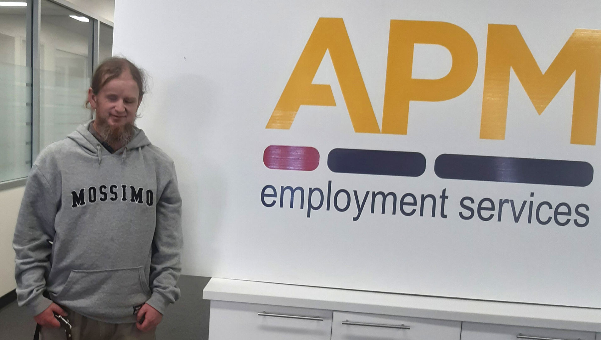 Ben standing in front of an APM Employment Services sign at his local APM office