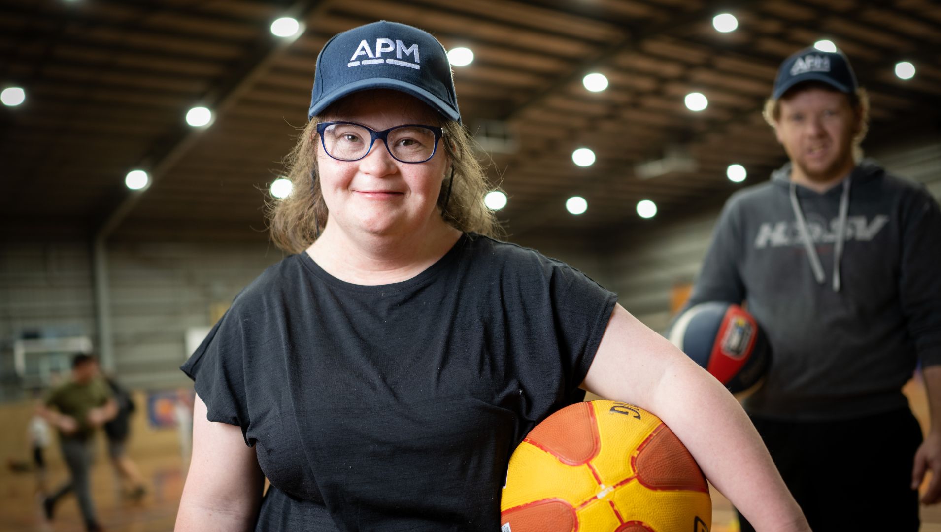 Holly smiling with a basketball and APM cap