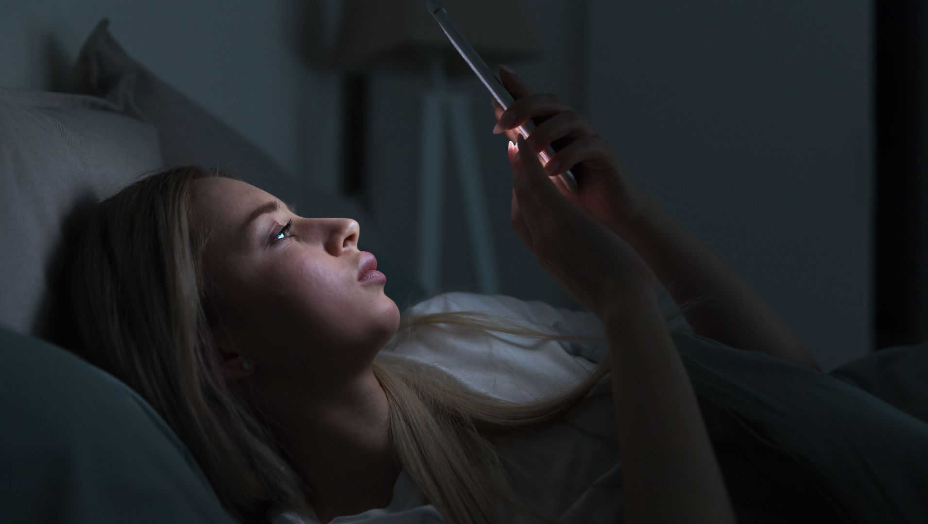Woman using a phone in bed when it is dark