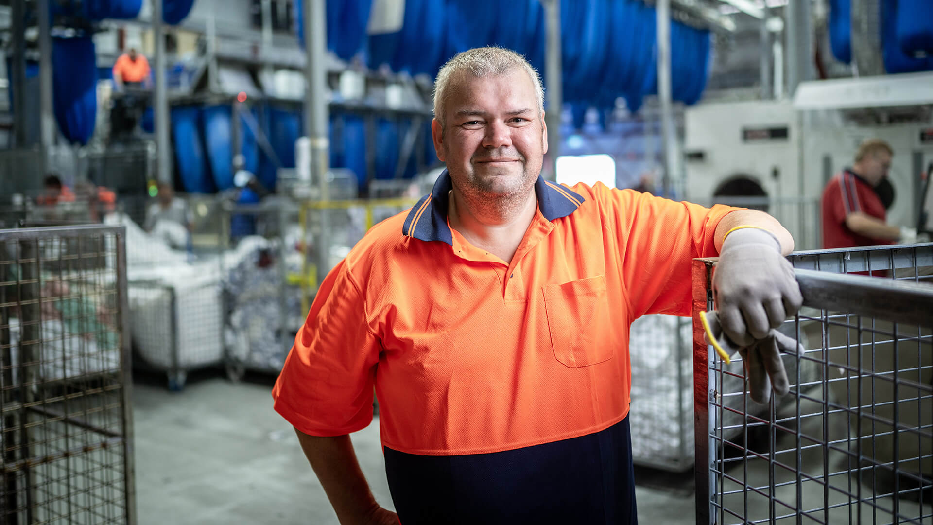 DES participant Geoffrey smiling in an orange shirt in a warehouse