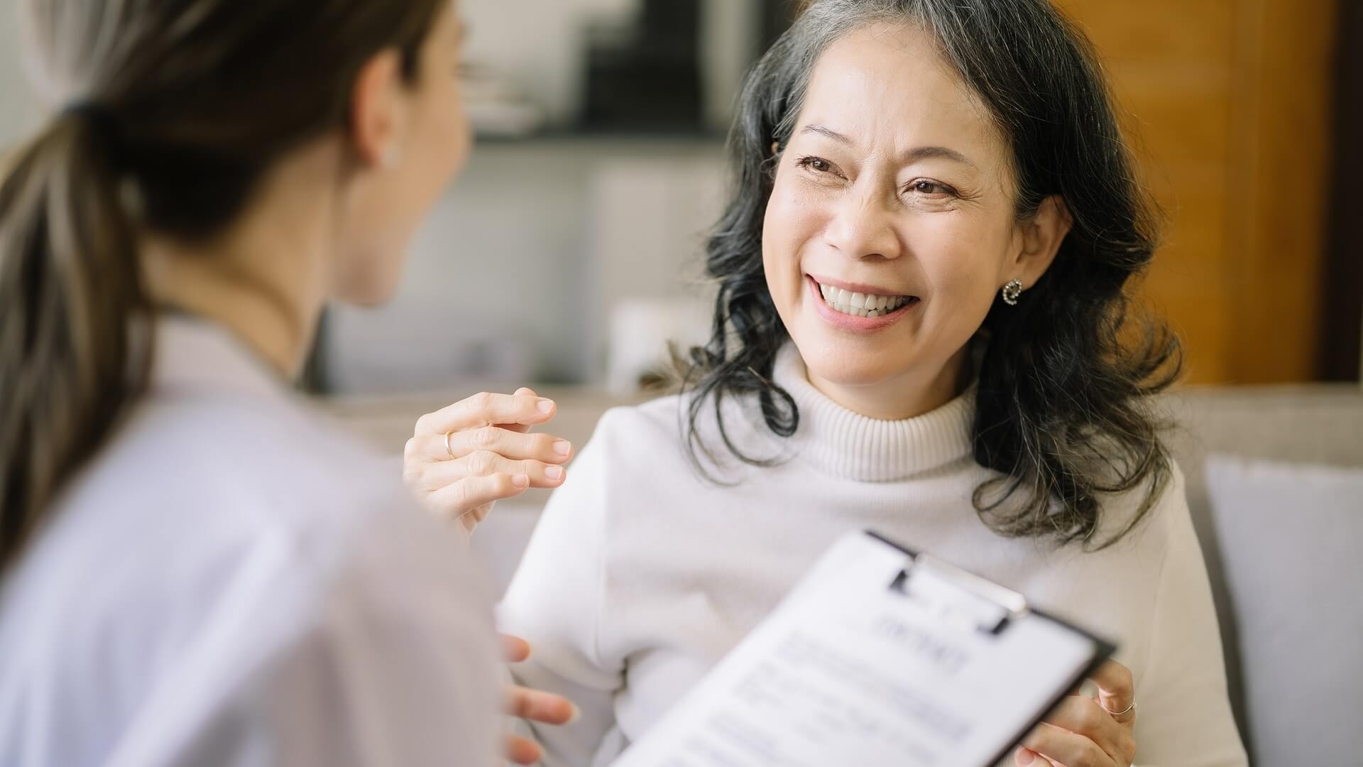 A smiling woman chats with her doctor