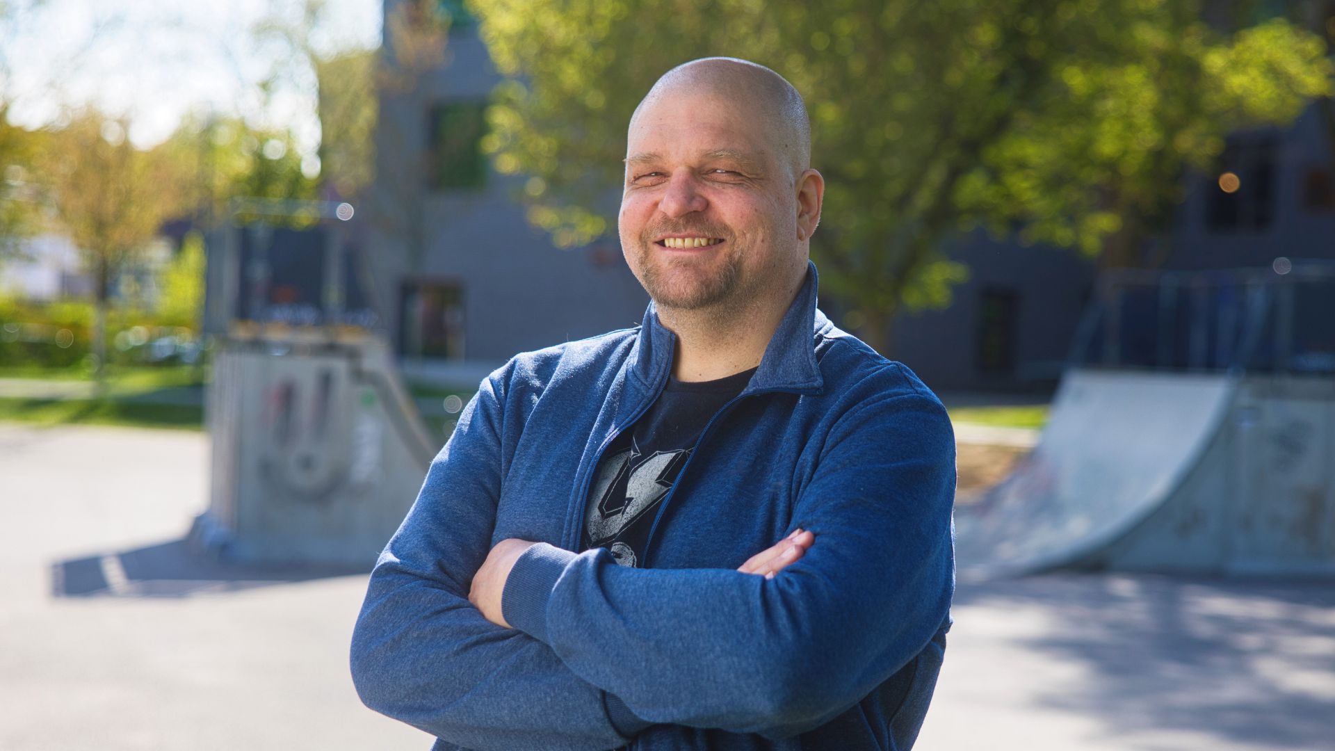 Marcel standing outdoors with arms crossed near a skate park, representing his journey with Ingeus Germany support.