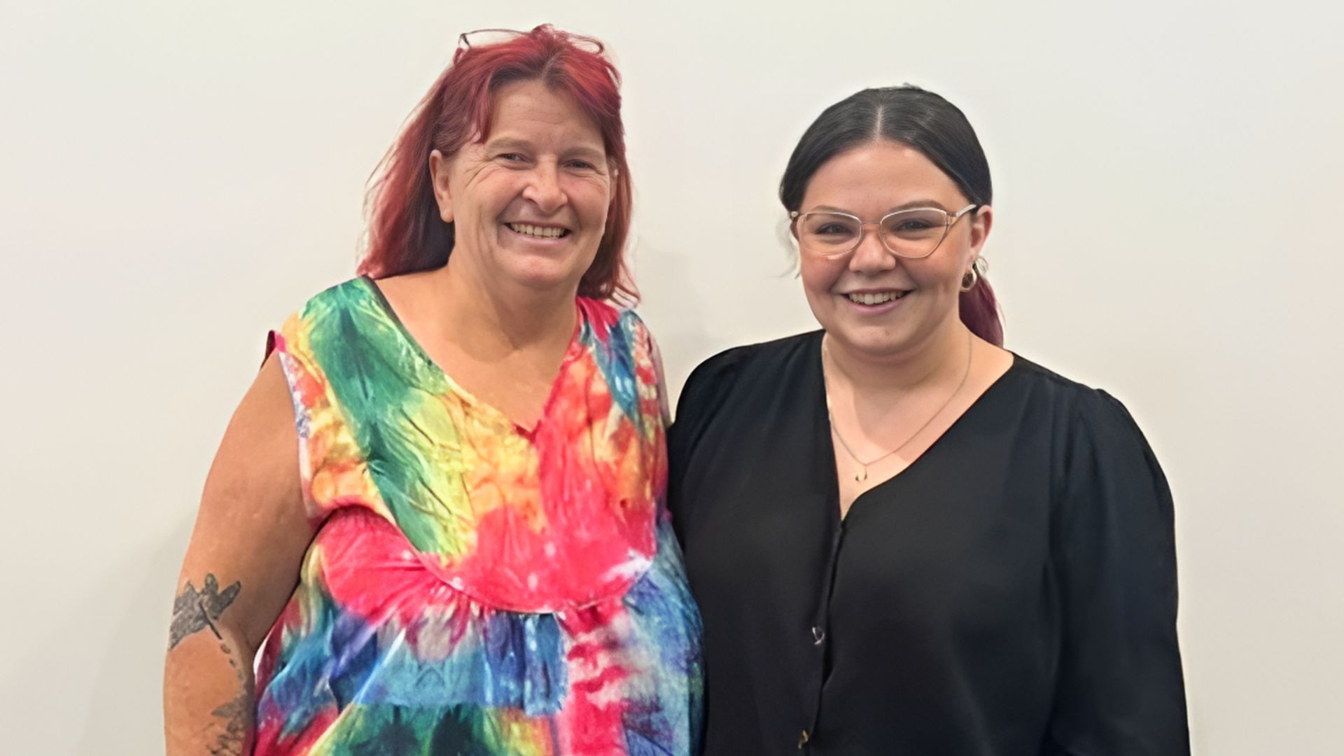 a woman in a colourful dress smiles next to an APM consultantea