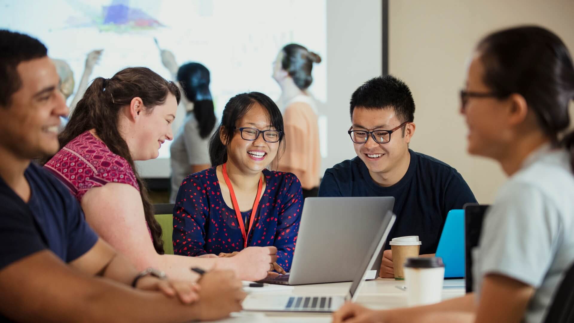 A group of five students happily studying around a table