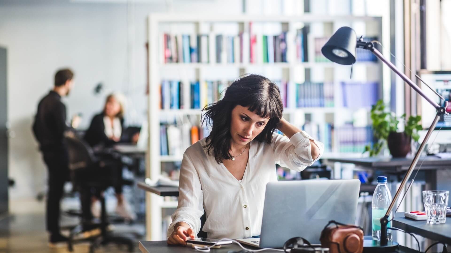 A stressed woman working on her laptop in an office